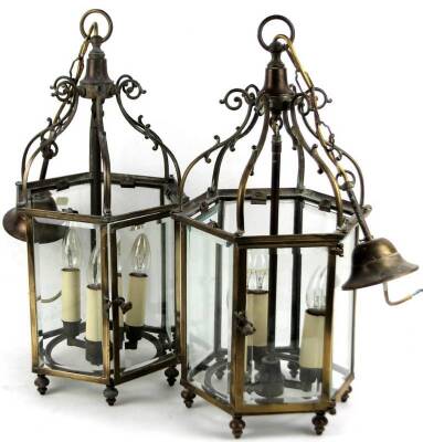 A pair of 19thC polished brass lanterns, each of hexagonal form with six glazed sections and three sconces, with a central ring fitting held by scroll supports, with later fittings, 63cm H. (2)