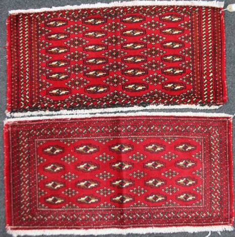 A matched pair of Torkaman rugs in red geometric pattern, 97cm x 45cm. (2)