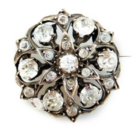 An Edwardian paste stone set circular brooch, with a floral centre, surrounded by paste stones, in a white metal frame, unmarked, 2.5cm W, 6.8g all in.