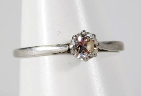 A solitaire dress ring, with round brilliant cut white stone, in claw setting with pierced shoulders on a white metal band, unmarked, Q-R.