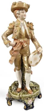 A continental porcelain figure, of a boy dressed in finery, on a naturalistic setting, holding tambourine, polychrome decorated predominately in green, blue and orange with gilt highlights, 24cm H.