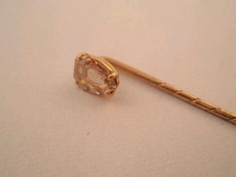 A stick pin in yellow metal topped by a faceted slice of champagne fancy diamond