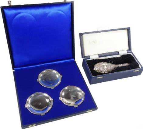 An Elizabeth II silver three piece pin tray set, A Quarter of The Century The Monarch's Reign, 1952, 1977 and 2002, 9cm W and a repousée decorated hairbrush with silver handle (cased).