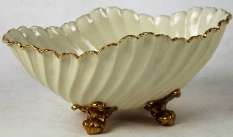 A late 19thC Royal Worcester porcelain shell shaped dish, with a ribbed body and gilt highlights, on scroll feet, purple marks beneath, 11cm H.