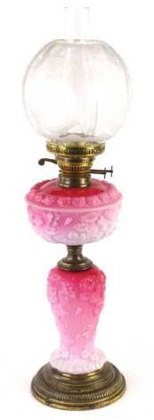 A Victorian pink opaque glass oil lamp, the Art Nouveau style frosted shade decorated with stylised fuscia leaves etc., the reservoir and base moulded in relief with poppies, on a gilt metal plinth, 72cm H.