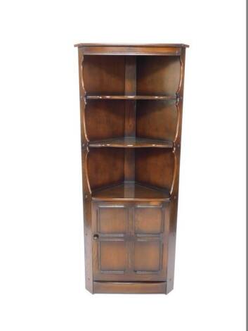 An Ercol dark oak corner cabinet, the pediment over two serpentine shelves, above a panelled door, enclosing a single shelf, raised on a plinth base, 82cm H, 73cm W, 42cm D.