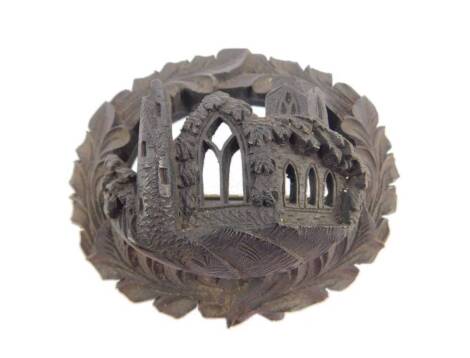 An Irish 19thC bog oak oval brooch, the pierced and carved design of an abbey, with leaf scroll borders, gilt metal pin, 6.5cm W.