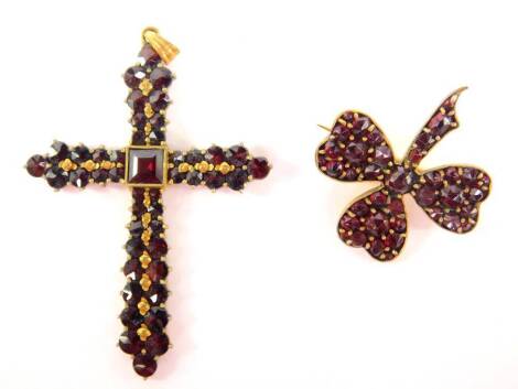 Two items of garnet set jewellery, comprising a garnet set crucifix pendant, marked to rear RF, gold plated, 3cm x 5cm, and a garnet set three leaf clover, in a yellow metal case, unmarked, 2.5cm wide.