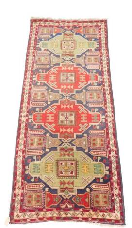 A Kazak runner, decorated with geometric motifs, against a blue ground, 305cm x 120cm.