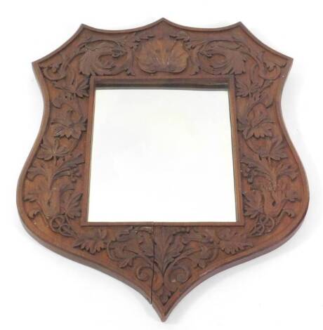 A Victorian oak shield shape wall mirror, carved with griffins heads, flowers and foliate scrolls.