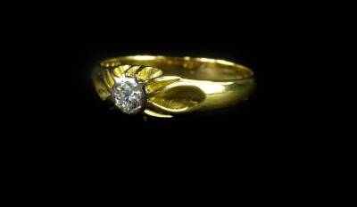 An 18ct gold diamond solitaire ring, the diamond in platinum rub over setting, with raised and waved design ring head, on a plain yellow metal band, the diamond approximately 0.21cts, ring size Y, 6.1g all in, boxed.