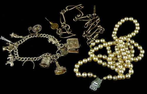 A small quantity of jewellery, comprising a silver watch chain, a silver charm bracelet, and a faux pearl necklace. (3)