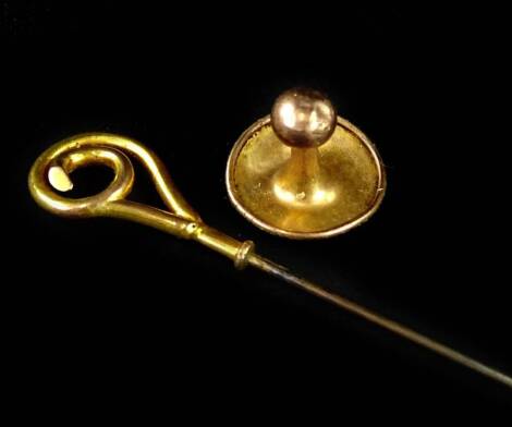 Two items of jewellery, to include a 9ct gold cufflink, and a hat pin, with yellow metal scroll design top. (2)