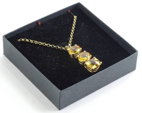 A three stone citrine pendant, the citrines of three stone drop, in a 9ct gold claw setting, the two oval cut citrines, 11.6mm x 9.6mm, with a rectangle cut paler stone to end, 11.8mm x 9.8mm, on belch link 9ct gold chain, the pendant 3.5cm H, on 9ct gold