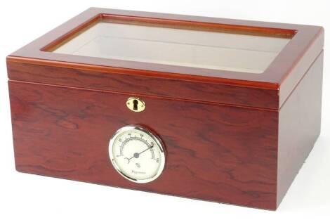 A glazed and veneered cigar humidor, the hinged lid enclosing various divisions, the front mounted with a hygrometer, 35cm W.