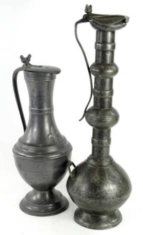 A large pewter flagon, with Middle Eastern influences, the slender neck terminating in a hinged lid with double acorn thumb piece, marks to underside, 57cm H, and a 19thC French pewter flagon, decorated to the front with a fleur de lys, the hinged lid wit