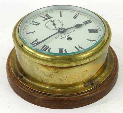 A ships bulk head timepiece, the white enamel dial stamped Berry and Mackay Aberdeen, with brass bezel, mounted onto later wooden backing, 19cm dia. Provenance: This timepiece formed part of Luke Jerram's installation Harrison's Garden, at The Ropewalk Ga