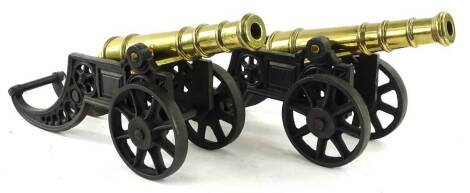 A pair of turned brass canon, the barrels 39cm L, each on a cast iron trunnion.