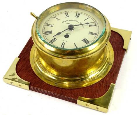 A brass bulkhead type ship's clock, the dial stamped Henry Browne & Sons, Barking & London, eight days, 16cm dia., mounted on a later plinth.