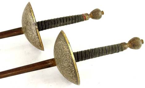 Two similar Continental fencing foils, the brass guards with chased decoration of scrolls, flowers etc.