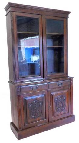 A Victorian walnut bookcase, the top with a moulded cornice with two glazed doors, the base with two frieze drawers and two carved panel doors, on plinth, 219cm H, 121cm W.