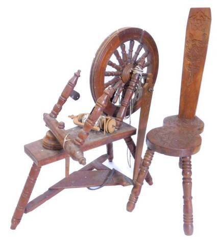 A 20thC carved teak spinning wheel, decorated overall with flowers etc., and a matching spinning chair.