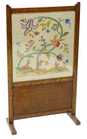 An early 20thC oak fire screen, with a crewel work insert, decorated with a squirrel, stag, butterfly, flowers etc., 54cm W.