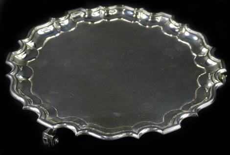 A George V silver waiter, with a pie crust border, on scroll feet, London 1911, 14¾oz, 23cm dia.