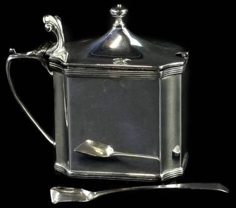 A canted rectangular silver mustard pot, with scroll cast thumb piece and turned finial, blue glass liner and associated spoon, London 1913, weighable silver 4¾oz.