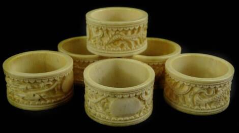 A set of six early 20thC Chinese Canton type ivory napkin rings, each decorated with the dragon, some with vacant cartouche.