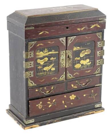 An early 20thC Japanese lacquer small cabinet, decorated in gilt with flowers etc., on a red ground, 30cm H, 24cm W.