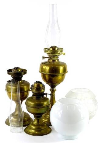 Three brass oil lamps, one with frosted shade, decorated with stars etc., another opaque