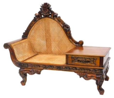 An Eastern hardwood telephone seat, with a caned back and seat, the frame carved with scrolls, flowers etc., on shaped feet, 139cm W.