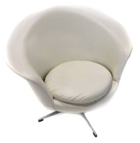 A retro style cream leatherette revolving tub type chair, on an x shaped metal base. The upholstery in this lot does not comply with the 1988 (Fire & Fire Furnishing) Regulations, unless sold to a known exporter or upholsterer it will be cut from the fram