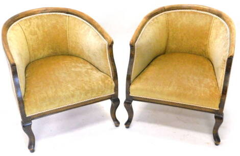 A pair of early 20thC beech tub shaped chairs, upholstered in beige fabric on cabriole legs.