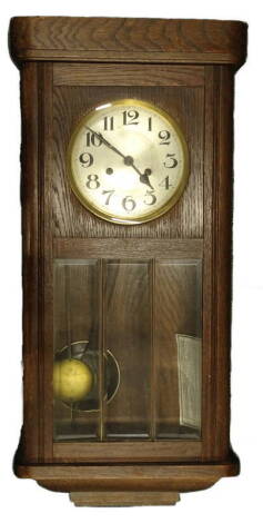 A 1920's oak cased wall clock, the silvered dial with Arabic numerals, above a glazed panel, 73cm H. Provenance: This timepiece formed part of Luke Jerram's installation Harrison's Garden, at The Ropewalk Gallery, Barton Upon Humber 2019.