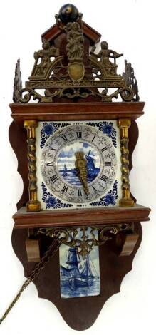 A Dutch wall clock, the top inset with a gilt metal figure of Atlas, the Delft type dial decorated with windmills, canals etc., of a similar plaque. Provenance: This timepiece formed part of Luke Jerram's installation Harrison's Garden, at The Ropewalk Ga