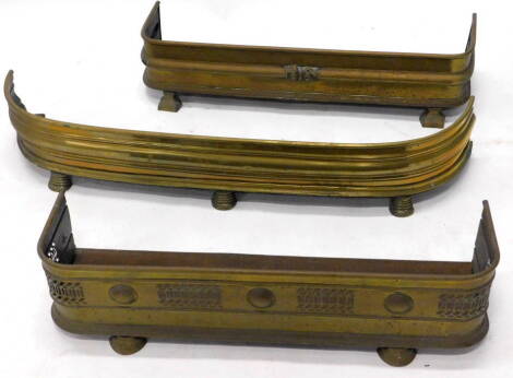 Three various late 19th/early 20thC brass fenders or fire kerbs, each on block feet.