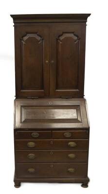 An 18thC and later walnut cabinet bookcase, with moulded cornice over two shaped and fielded panelled doors revealing pigeonholes and vertical dividers, over two candle slides with knob handles, the rectangular fielded panel fall flap reveals staged drawe