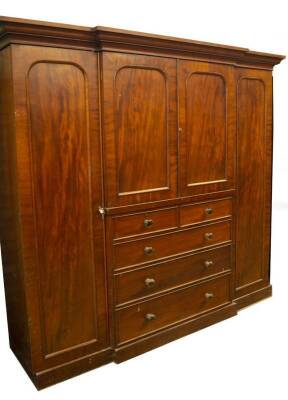 A Victorian mahogany breakfront wardrobe compactum, with moulded cornice, full length panelled doors flanking a centre of two similar arch panelled doors, revealing press drawers over two short and two long graduated drawers with pressed glass knob handl