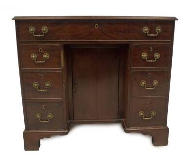 A George III mahogany kneehole desk, with oak lined frieze drawer, and a bank of three drawers to each pedestal, with brass pierced and cast swan neck handles, the cupboard centre revealing shelves, on bracket feet, 84cm H, 95cm W, 55cm D.