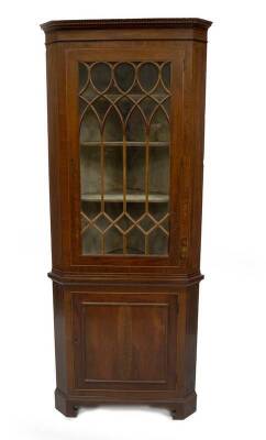 A George III mahogany standing corner cupboard, with dentil moulded cornice, astragal glazed single door with flamed banding surround, string inlay and later moulded panel base on bracket feet, 194cm H, 80cm W around the canted corners.