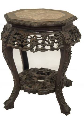 A 19thC Chinese hardwood jardiniere stand, with grey and liver marble inset hexagonal top, having carved prunus decoration, dragon masks and leaves to the framing and undershelf, 48cm H, 40cm Dia to the top.