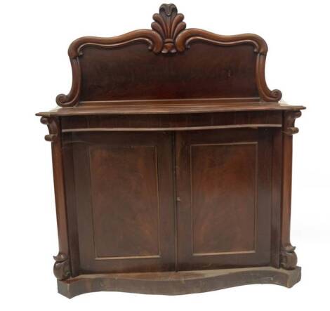 A Victorian flame mahogany serpentine chiffonier, with stylised carved scrolling panel back, frieze drawer, over a two moulded door base, on serpentine plinth, 82cm servery height, 128cm W, 45cm D.