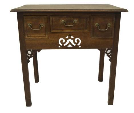 A George III oak lowboy, with moulded top over three drawers with mahogany stringing and brass swan neck handles, fretwork panel and applications on chamferred square legs, 72cm H, 75cm W, 51cm D.