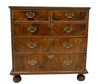 A George II oak chest, of two short and three long graduated drawers, with walnut veneer and crossbanding, having pierced brass back plate loop handles, on ball feet, 83cm H, 94cm W, 54cm D.