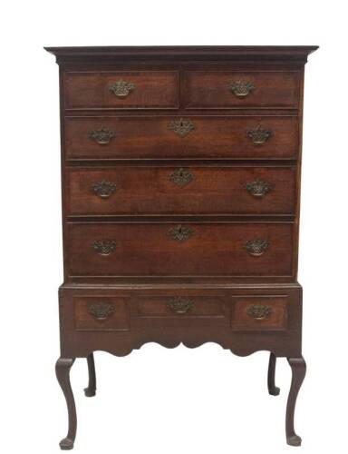 A George III oak chest on stand, with moulded cornice, over two short and three long graduated cock beaded drawers with mahogany cross banding, pierced brass back plate handles and matching escutcheons, the lower part having an arrangement of three drawer