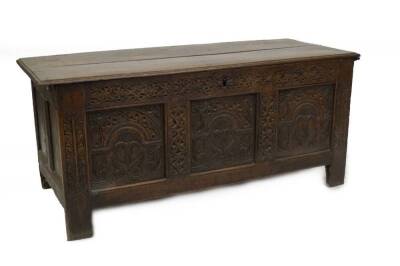 A late 17thC oak coffer, with plank top, Arabesque carved frieze, over three panels with arched decoration and stylised trees, and part carved stiles, 64cm H, 145cm W, 60cm D.