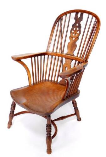 An early 19thC ash, elm and fruitwood high back Windsor chair, probably North Lincolnshire or East Riding of Yorkshire with wheel back splat, crook arms, deep saddle seat, ring turned legs and crinoline stretcher, 62cm over arms, the seat 60cm deep includ