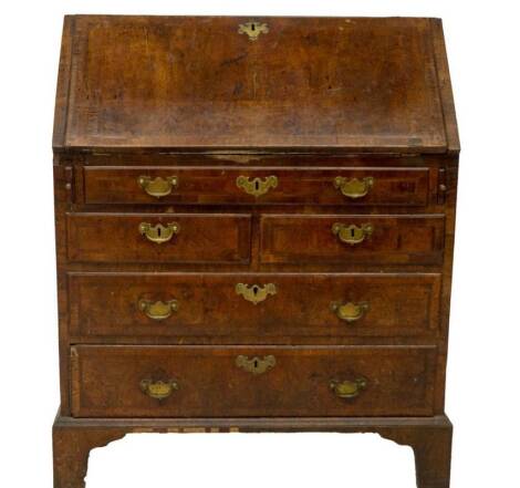 A George III walnut bureau, with herringbone inlay and cross banded top and fall flap resting on lopers revealing a fitted interior with pigeon holes drawers cupboard and secret compartments, over one long two short and two long graduated drawers with br